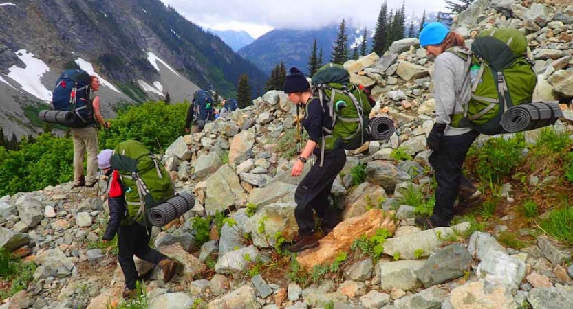 a group of teens crossing rocking terrain on outward bound backpacking expedition